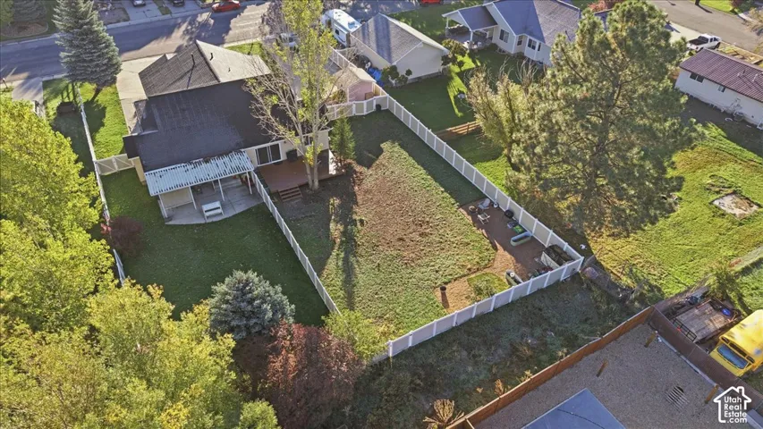 Fenced backyard featuring an expansive lawn, a wood deck, a paved patio area, and mature trees