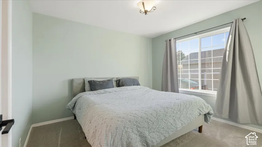 Neutral-toned walls, wall-to-wall carpeting, large picture window, and a ceiling-mounted light fixture