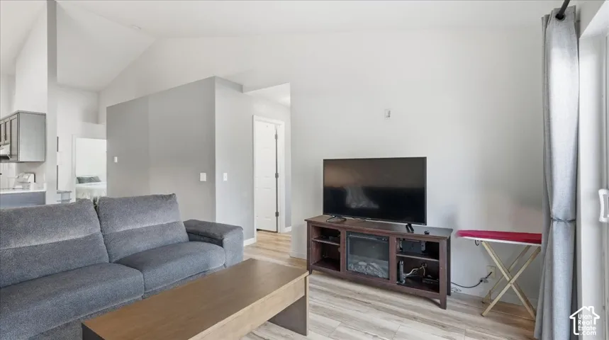 Vaulted ceiling, wood-finish flooring, and neutral wall tones