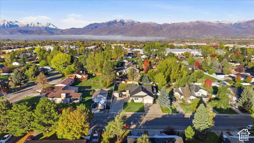 Aerial perspective featuring a residential lot with a paved driveway, attached garage, and mountain backdrop