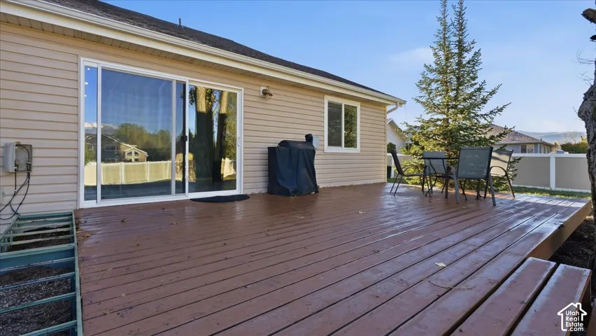 Rear exterior featuring a wood-plank deck, horizontal vinyl siding, sliding glass doors, and a perimeter privacy fence