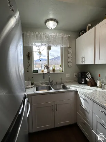 Kitchen featuring white Shaker-style cabinetry, stone-patterned laminate countertops, a double-basin stainless steel sink with a pull-down faucet, and recessed ceiling lighting