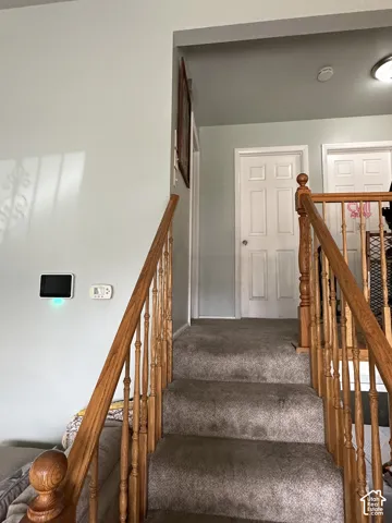 Staircase featuring natural wood handrails and turned balusters, neutral carpeting, and two six-panel interior doors