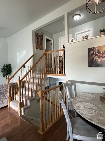 Interior staircase featuring wooden handrails, turned balusters, carpeted treads, and wood-finish flooring