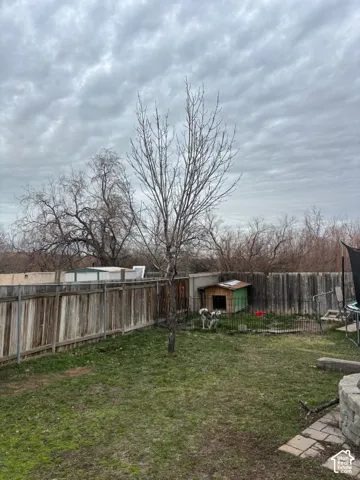 Backyard featuring wood fencing, mature trees, and a stone paver patio