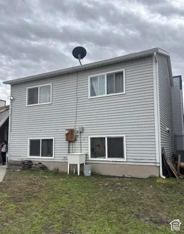 Two-story residential exterior featuring light gray horizontal siding, sliding windows with white trim, and a concrete foundation