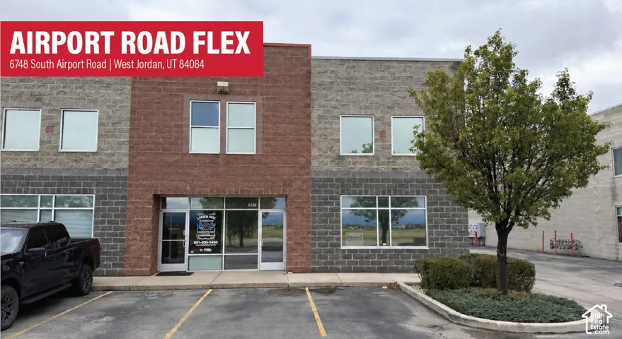 Two-story commercial exterior featuring split-faced masonry, full-height storefront glass, paved parking, and established landscaping