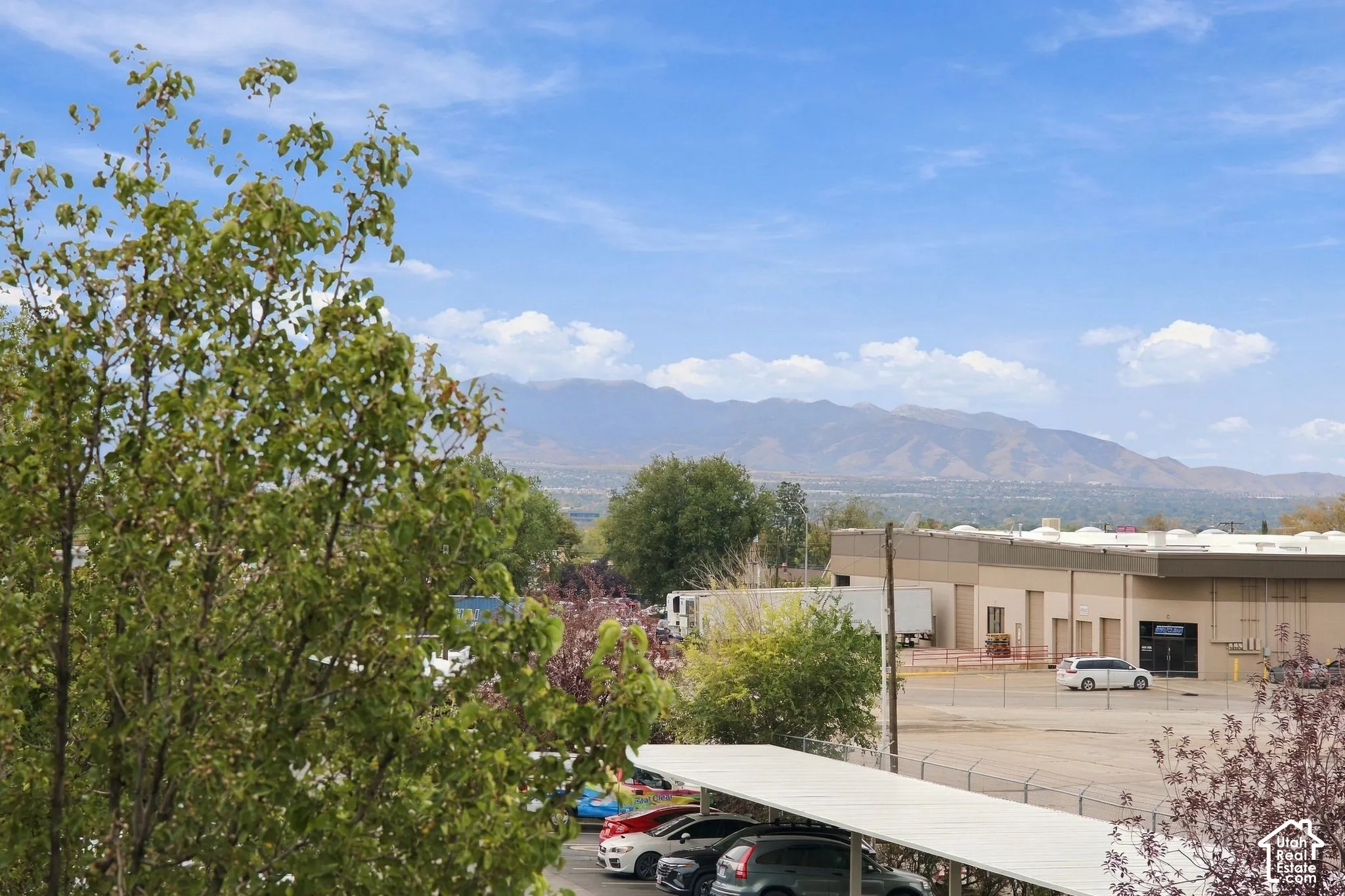 Mountain backdrop with open sky exposure, deciduous trees, and metal-roofed vehicle carports