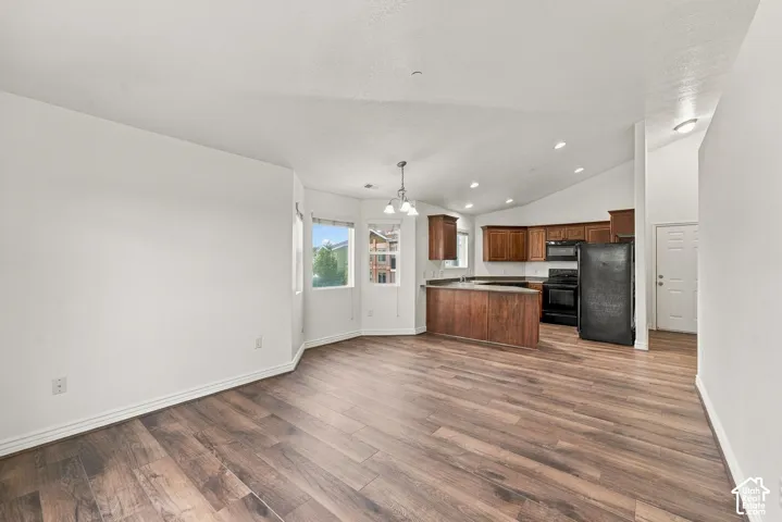Vaulted ceilings, wood-finish flooring, kitchen featuring wood cabinetry and peninsula, and bay-style windows