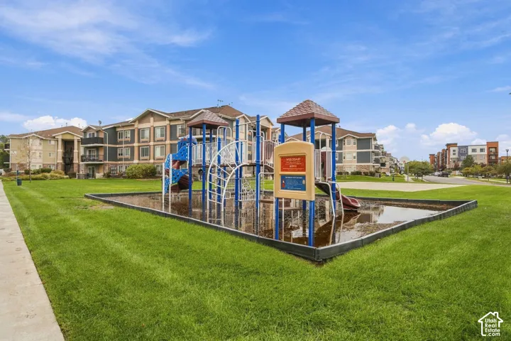 Common area featuring a playground structure, surrounding manicured lawn, and concrete walkways