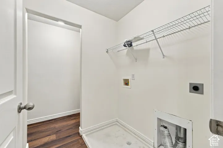 Laundry area featuring wood-finish flooring, white walls, built-in wire shelving, and dedicated utility connections