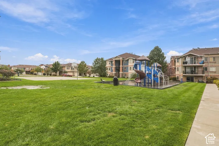 Community grounds featuring a multi-structure playground, expansive green space, concrete walking paths, and mature landscaping