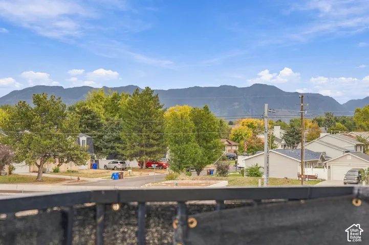 Black metal railing overlooking an expansive mountain backdrop and mature trees