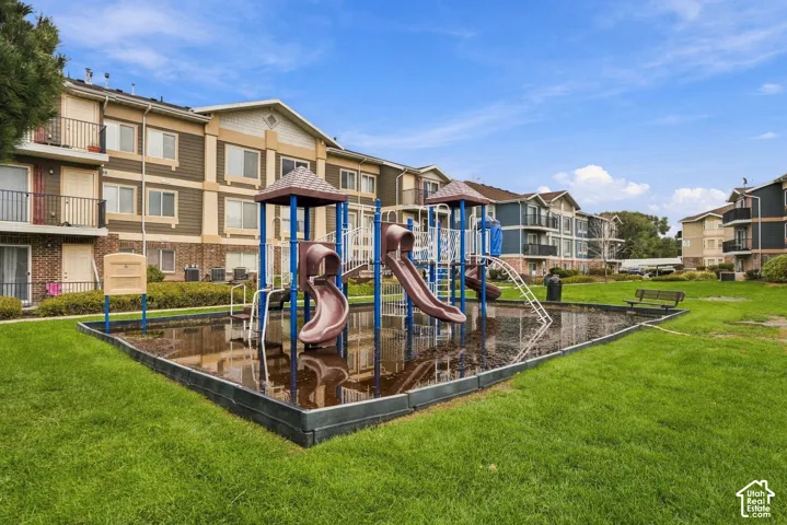 Communal recreation area featuring a playground structure with slides, integrated landscape curbing, and manicured green space