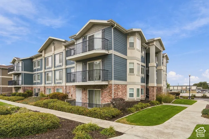 Multi-story building exterior featuring horizontal siding, brick masonry cladding, private balconies with iron railings, and concrete walkways