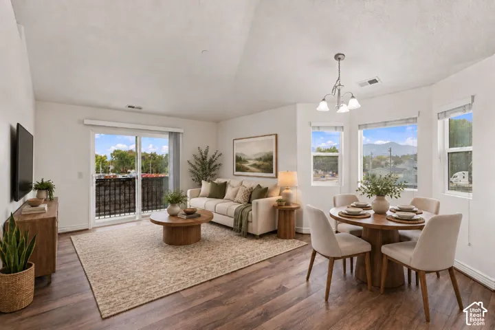 Open-concept room featuring vaulted ceilings, wood-finish flooring, sliding glass doors to a balcony, and a multi-pane bay window assembly