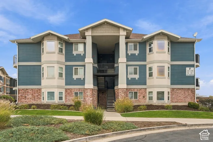 Multi-story exterior featuring blue horizontal siding, brick masonry detailing, prominent bay window projections, and shingled gables