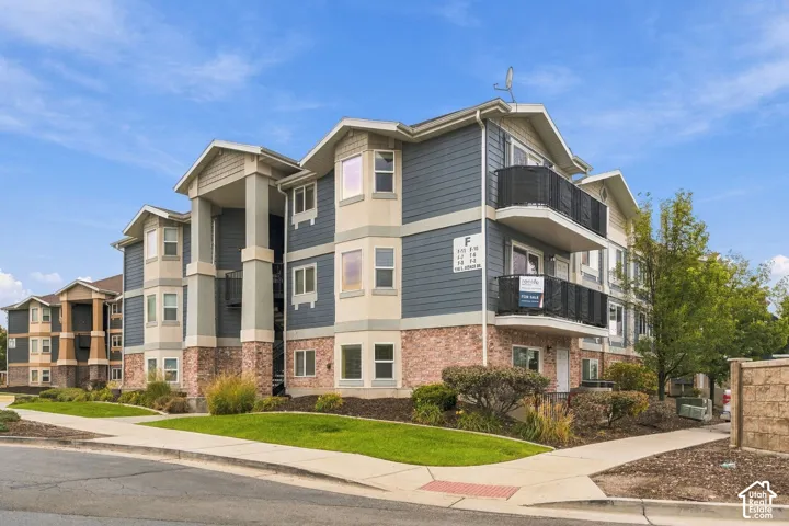 Multi-story building exterior featuring a mixed-material facade of lap siding, stone masonry, and shingle accents, complemented by private balconies with black railings