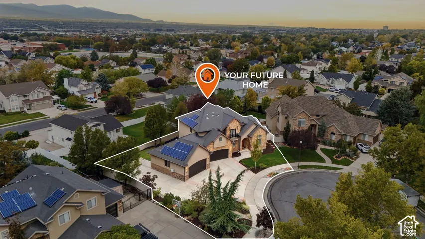 Aerial perspective of a multi-story residence featuring solar panel arrays, stone and stucco exterior, a multi-car garage, and a concrete driveway