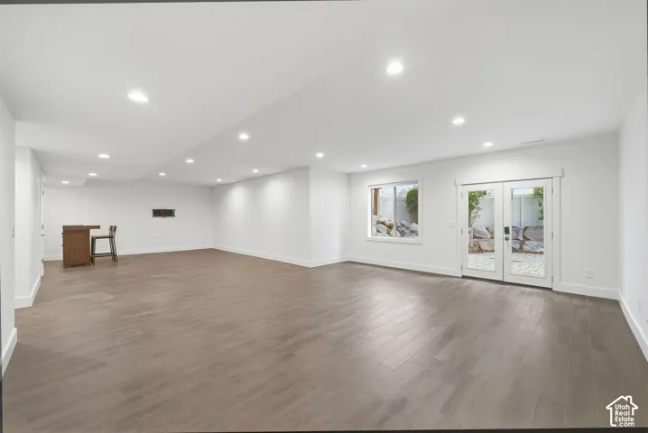 Open interior space featuring wood-finish flooring, recessed lighting, double French doors, and a built-in wet bar