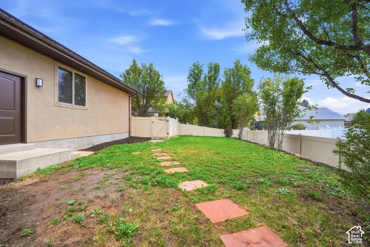 Stucco exterior finish with a concrete step, stone-paver walkway, and vinyl perimeter fencing