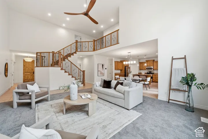 Two-story living area featuring a vaulted ceiling, a wooden staircase with iron balusters, recessed lighting, and a multi-blade ceiling fan