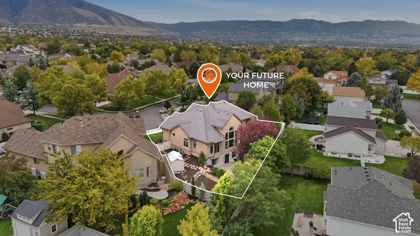 Multi-story residence featuring a shingled roof, stucco exterior, expansive windows, hardscaped patio area, and mountain backdrop