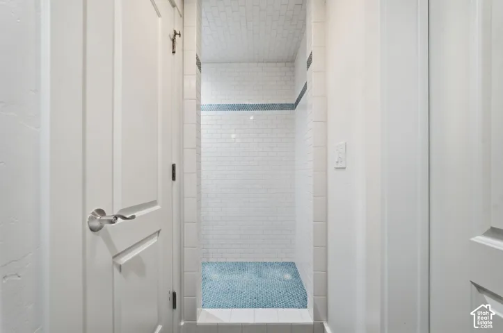 Walk-in shower featuring white subway wall tile, blue mosaic floor tile, and a decorative blue tile accent border
