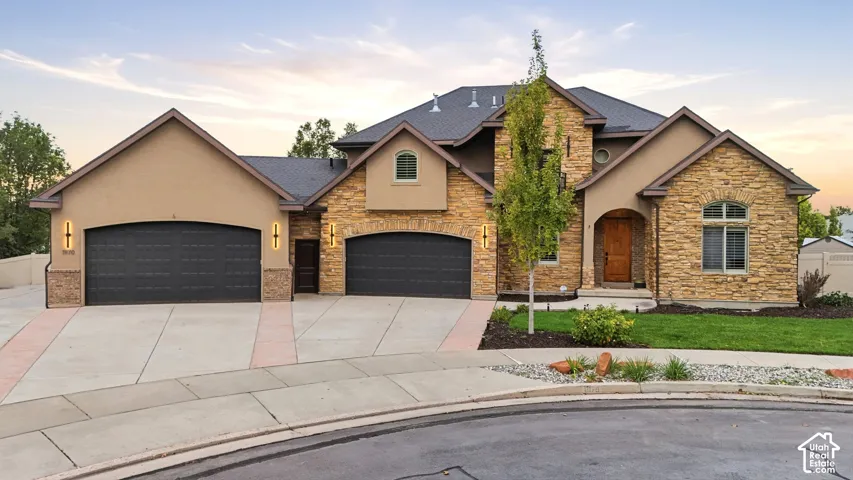 Exterior facade featuring stone veneer masonry, dual garage bays, arched entryway with a solid wood door, and a multi-gabled roofline