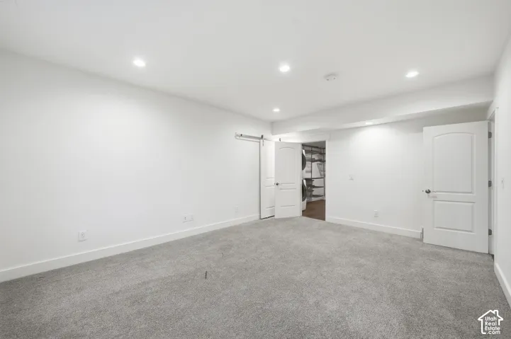 Interior space featuring recessed lighting, neutral carpeting, sliding barn door, and classic paneled doors