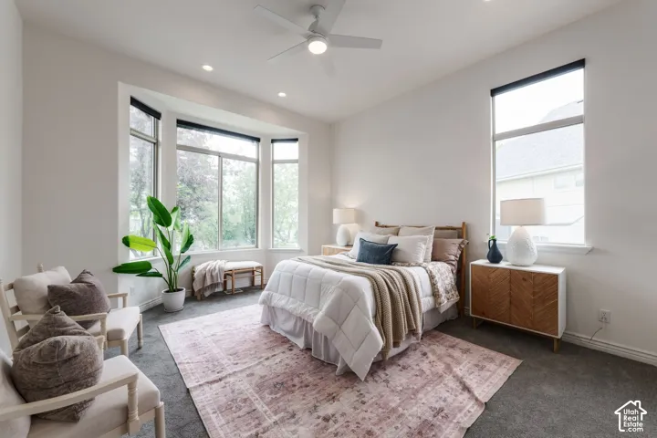 Room featuring neutral wall tones, carpeted flooring, a multi-pane bay window, recessed lighting, and a ceiling fan