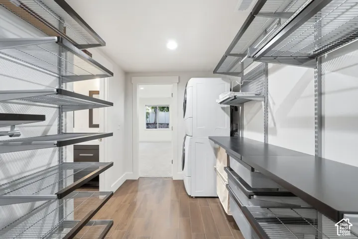 Utility room featuring wood-finish flooring, modular metal wire shelving, and a built-in solid surface countertop