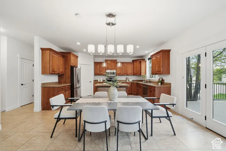 Kitchen featuring warm-tone wood cabinetry, stone countertops, stainless steel appliances, a central kitchen island, and ceramic tile flooring