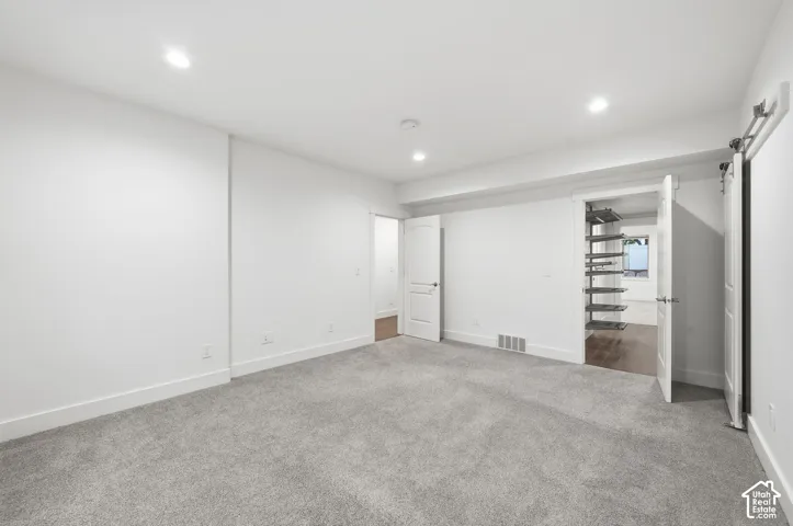 Interior room featuring neutral carpeting, recessed lighting, and a built-in closet system