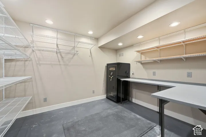 Storage room featuring wire shelving, built-in workbench, recessed lighting, and a floor-mounted heavy-duty security safe