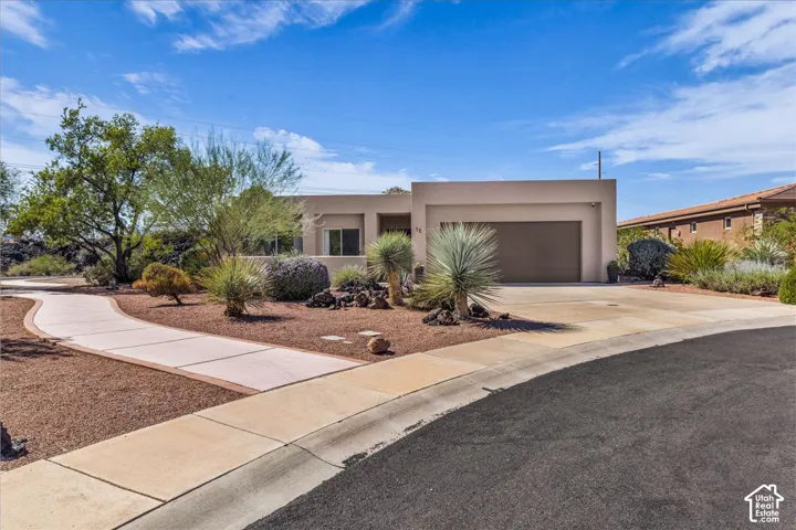Contemporary stucco exterior with an integrated garage, a curved concrete driveway, and desert landscaping