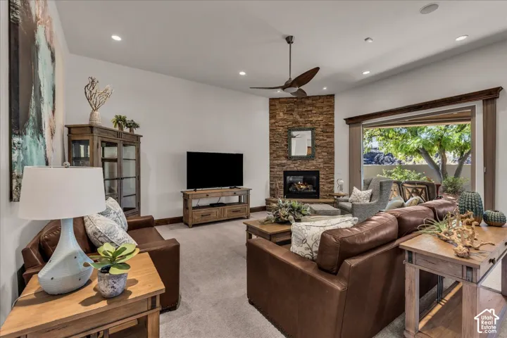 Living area featuring a floor-to-ceiling stacked stone fireplace, a ceiling fan, recessed lighting, and a large multi-panel sliding glass door