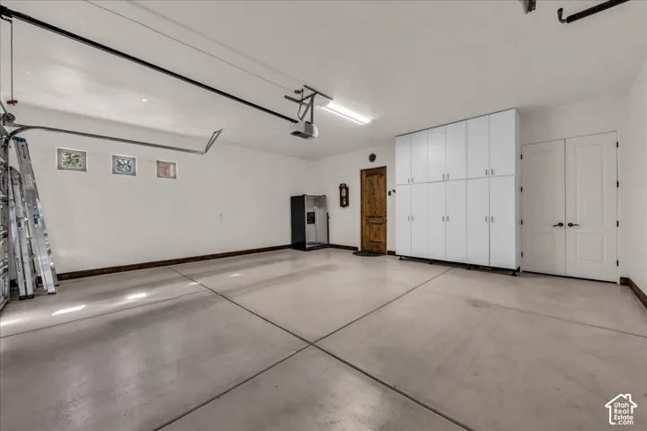 Concrete flooring with expansion joints, built-in white cabinetry, natural wood-finish door, and white panel doors