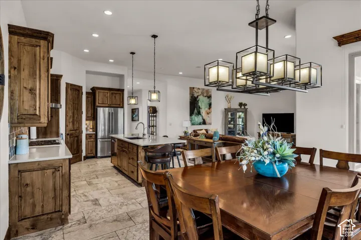 Open-concept living space featuring wood-finish cabinetry, a kitchen island with seating, stainless steel appliances, and tile flooring