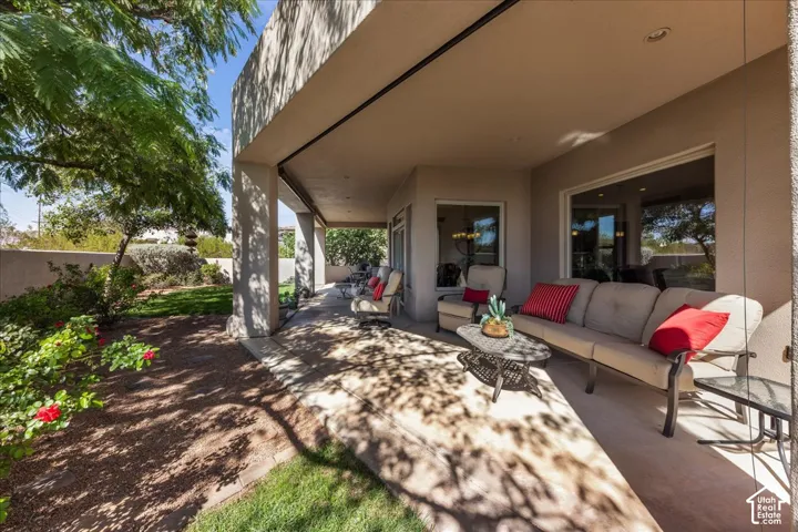 Covered patio with recessed lighting, large glass windows, and mature landscaping
