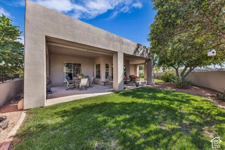 Expansive backyard with a manicured lawn, covered patio, and established trees