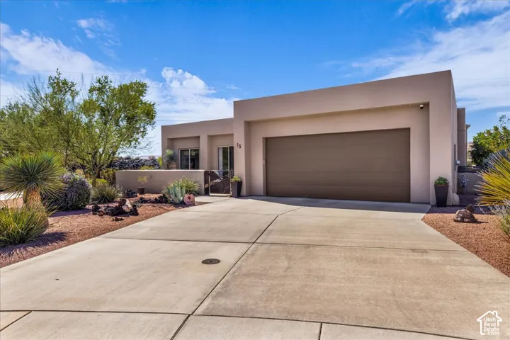 Stucco exterior, integrated garage, concrete driveway, and desert landscaping