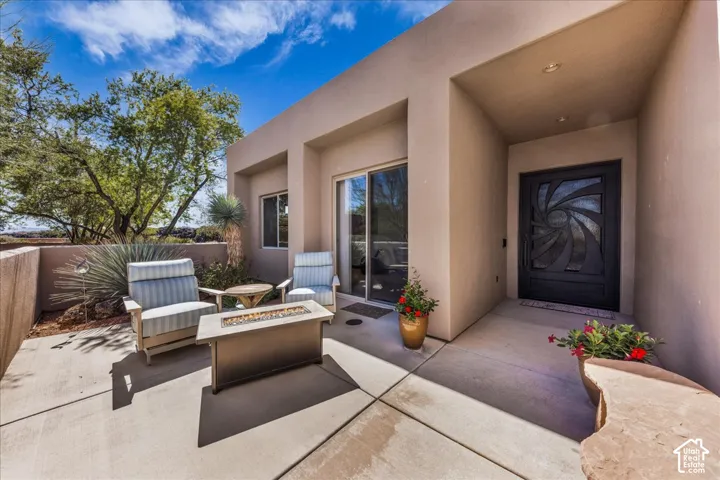 Stucco exterior featuring an ornate black entry door, recessed entry, and a concrete patio