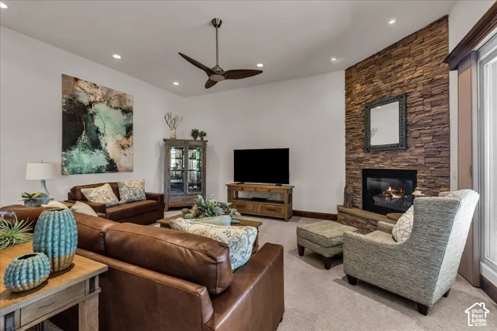 Stone-clad fireplace with a hearth, recessed lighting, and a sloped ceiling with a ceiling fan