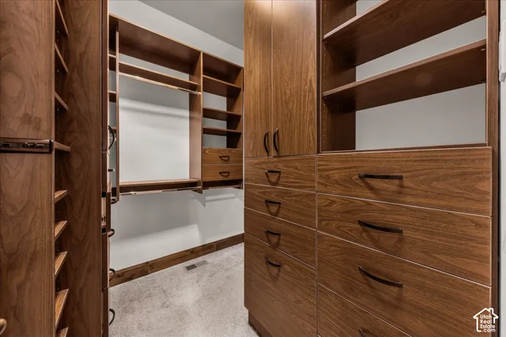 Built-in closet system featuring wood-finish cabinetry, multiple drawers with dark hardware, varied shelving, and hanging rods