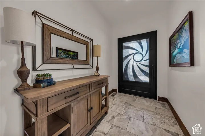 Black entry door with patterned glass, light-toned tile flooring, and light-toned walls