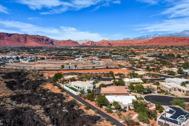 Expansive desert landscape with mountainous backdrop, featuring numerous single-story properties, and established roadways