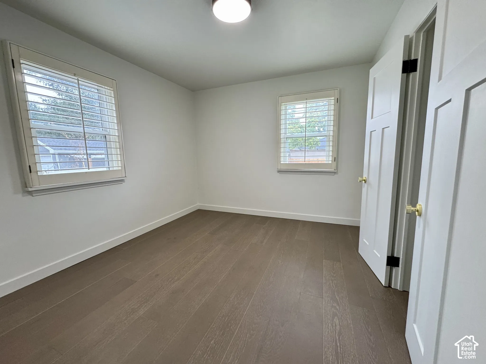 Main level bedroom with real wood flooring, white paneled doors, and window plantation shutters