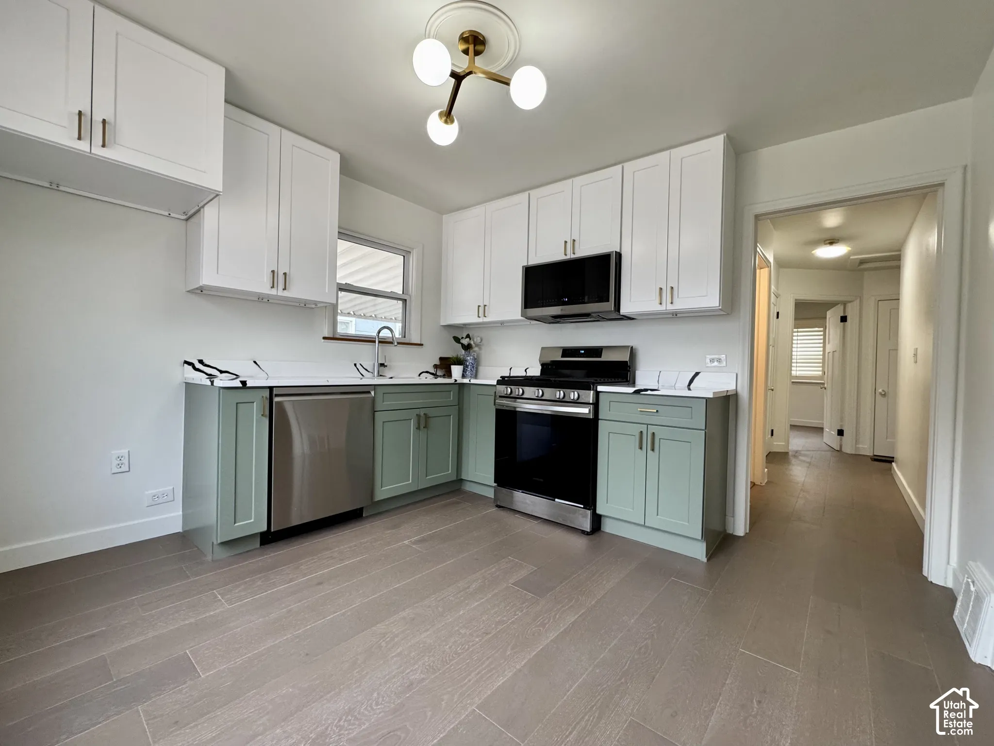 Newly remodeled kitchen with new soft close cabinetry, real wood floors and stunning quartz countertops. New stainless steel appliances