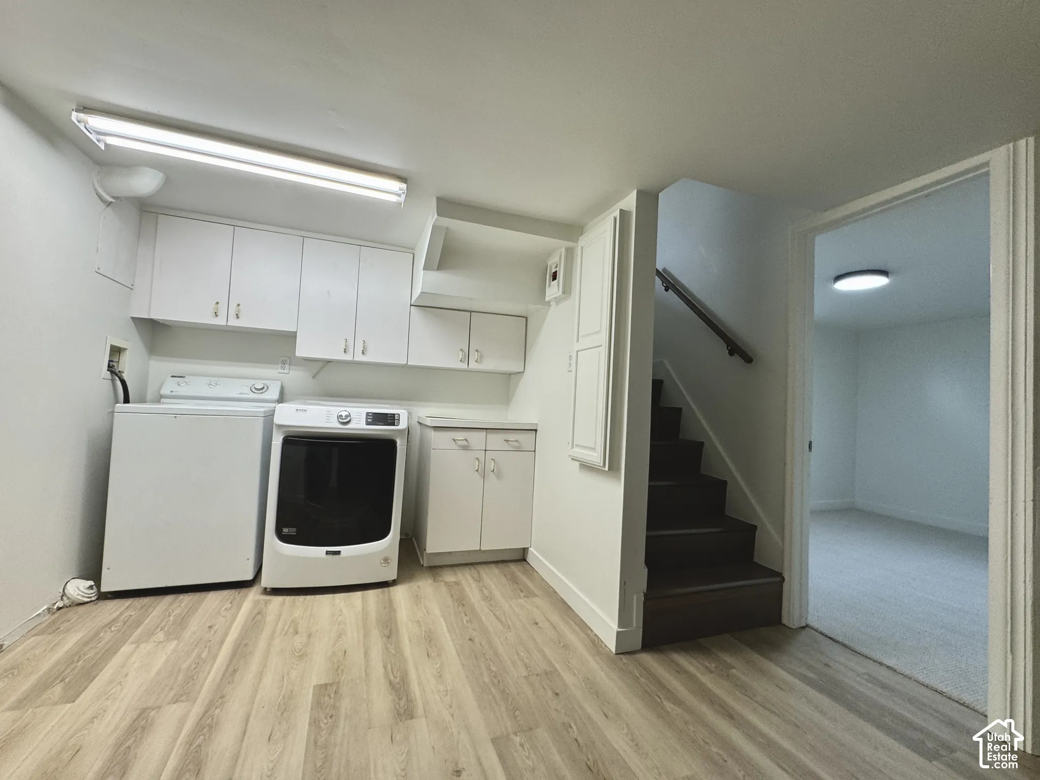 Laundry area featuring white shaker-style wall and base cabinetry, and LVP flooring